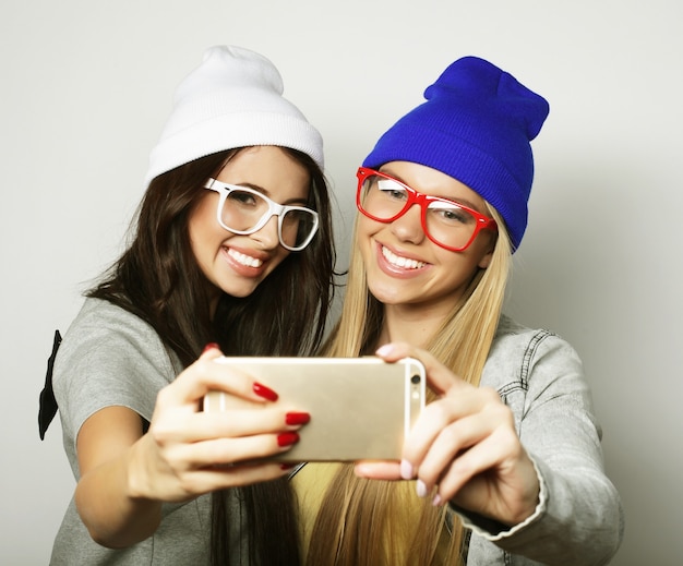 Twee tienermeisjes vrienden in hipster outfit maken selfie op witte achtergrond