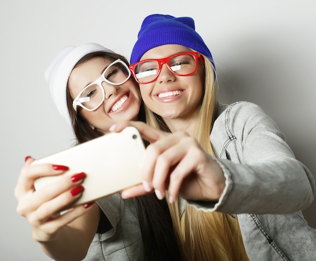 Twee tienermeisjes vrienden in hipster outfit maken selfie op witte achtergrond