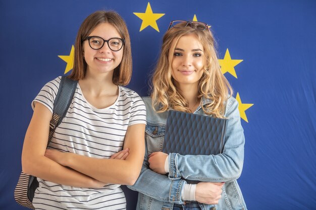 Twee tienermeisjesstudenten staan voor de vlag van de Europese Unie.