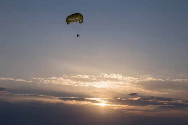 twee toeristen parasailen over de zee tijdens zonsondergang