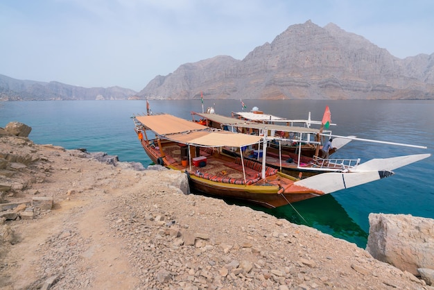 Foto twee traditionele arabische dhow-boten geparkeerd bij een eiland in een turquoise fjord op een nevelige dag