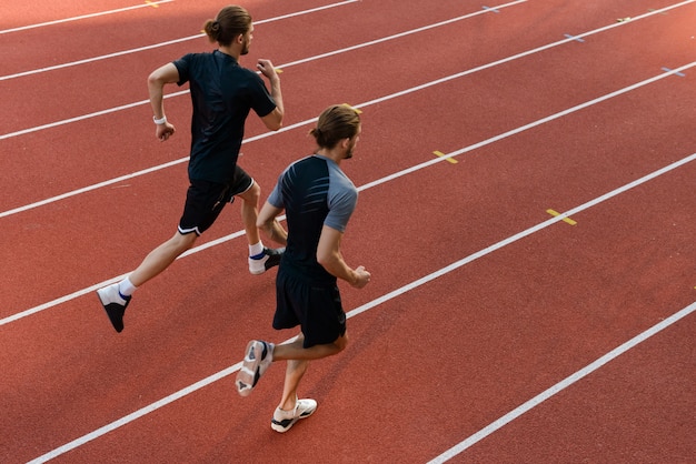 Twee tweelingbroers sporters die in het stadion buiten rennen.