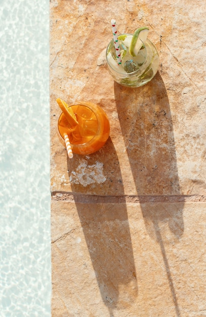Twee verfrissende cocktails bij het bovenaanzicht van een zwembad