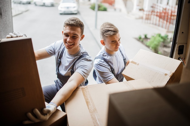 Twee verhuizers in uniform zijn het busje vol dozen aan het uitladen