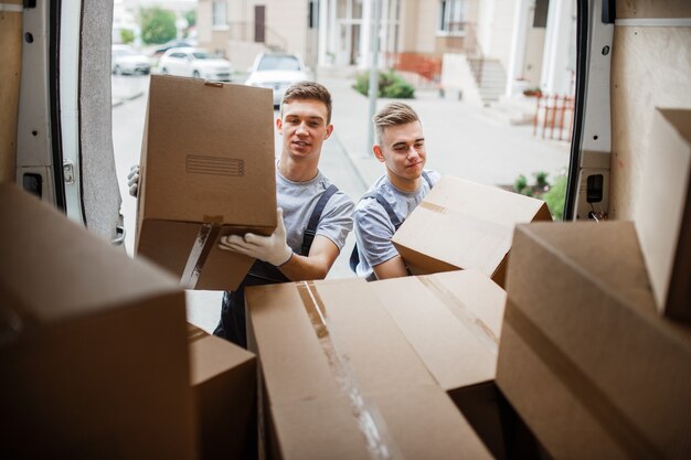 Twee verhuizers in uniform zijn het busje vol dozen aan het uitladen