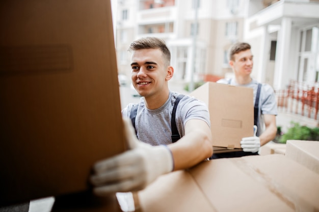 Twee verhuizers in uniform zijn het busje vol dozen aan het uitladen