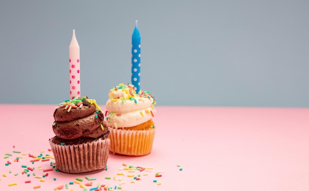 Twee verjaardag cupcakes met kaarsen op blauwe en roze pastel achtergrond kopie ruimte