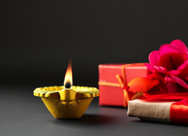 Foto twee verlichte indiase aarden lampen en een elegant verpakte geschenkdoos en bloem. diwali is het grootste hindoefestival dat wordt gevierd