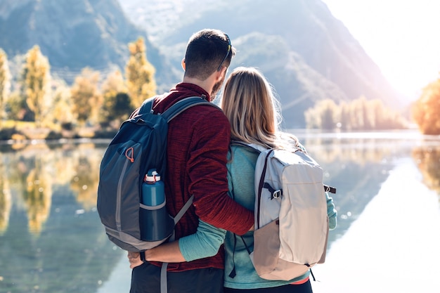 Twee verliefde reizende wandelaars genieten van de natuur terwijl ze het landschap voor het meer in de bergen bekijken.