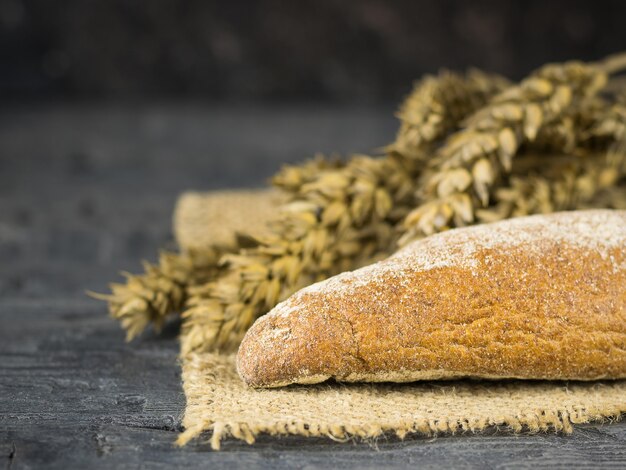 Twee vers gemaakte stokbrood van tarwemeel op een stuk jute met oren op de donkere houten tafel