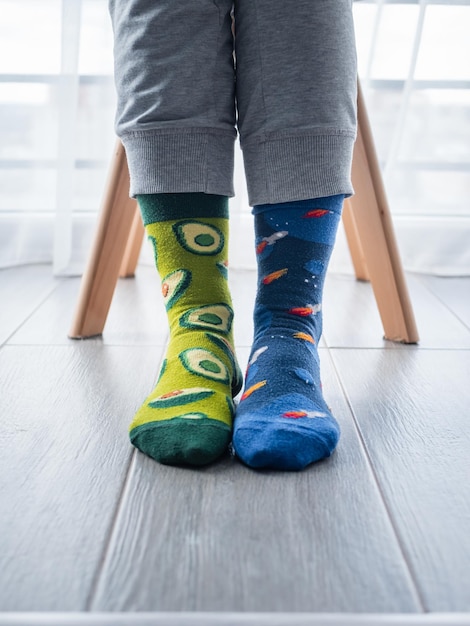 Twee verschillende artistieke sokken op voeten, met avocado's aan de linkerkant en blauwe ruimte aan de rechterkant