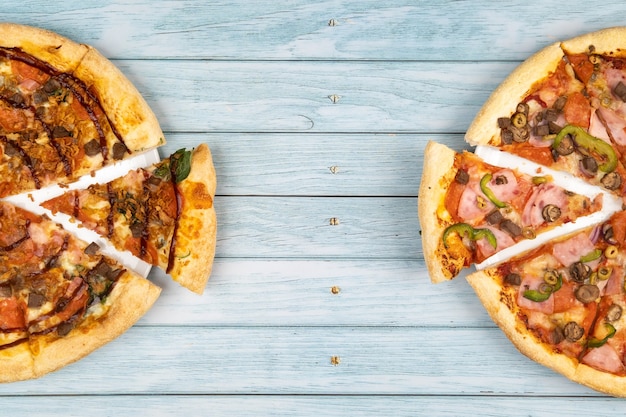 Twee verschillende heerlijke grote pizza's op een blauwe houten achtergrond.