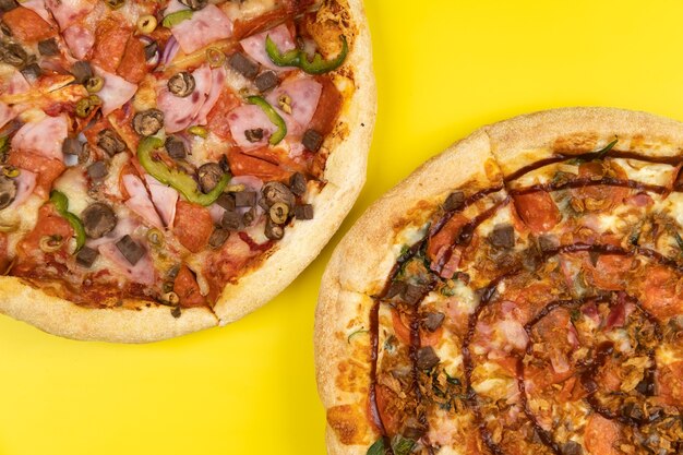 Twee verschillende heerlijke grote pizza's op een gele achtergrond.