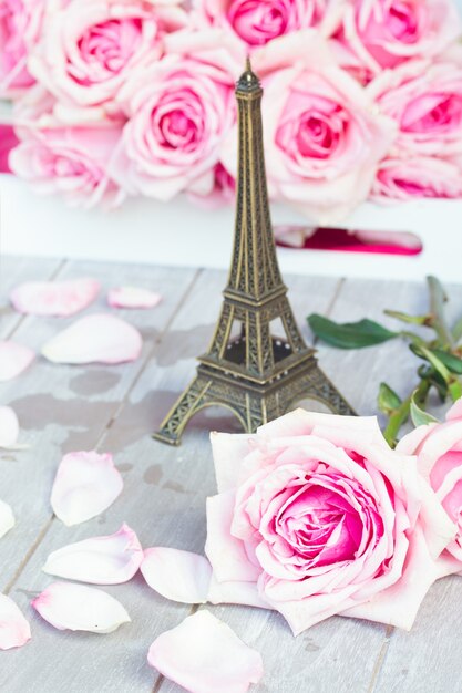 Twee verse bloeiende roze rozen die op houten lijst met de reis van Eiffel leggen - reisconcept