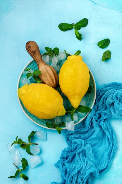 Twee verse citroenen in blauw bord op turquoise betonnen ondergrond. Voedsel achtergrond.