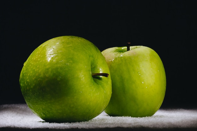 Twee verse groene appels op een donkere achtergrond