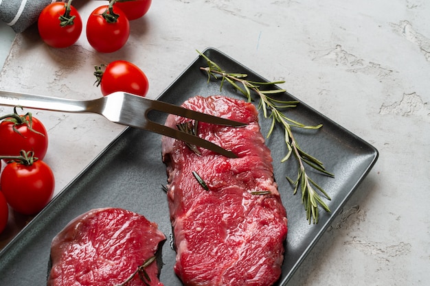 Twee verse rauwe vlees steaks op zwarte keramische plaat