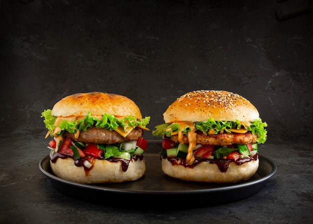 Twee verse smakelijke hamburgers op donkere achtergrond