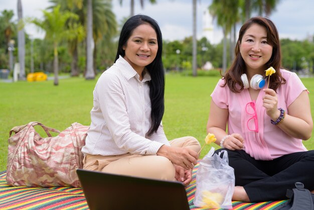 Twee volwassen Aziatische vrouwen ontspannen samen in het park