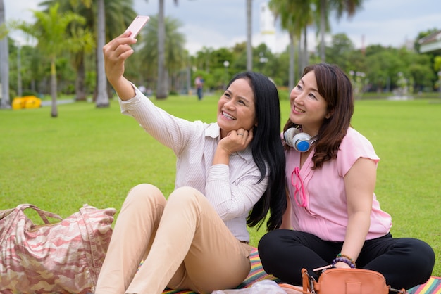 Twee volwassen Aziatische vrouwen ontspannen samen in het park