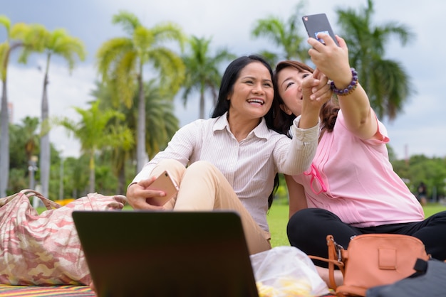 Twee volwassen Aziatische vrouwen ontspannen samen in het park