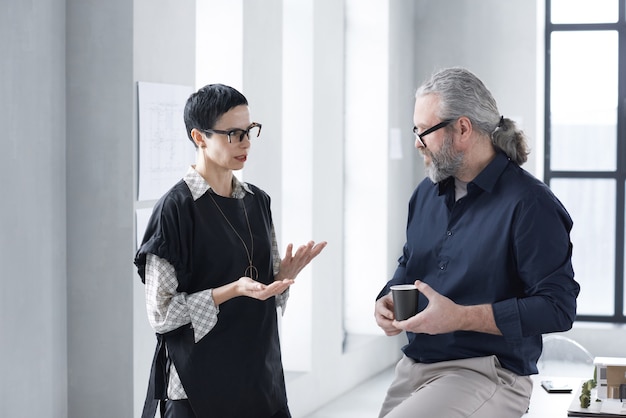 Twee volwassen collega's bespreken hun werk op modern kantoor