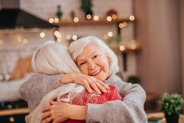 Twee volwassen grijsharige positieve dames die zich gelukkig voelen