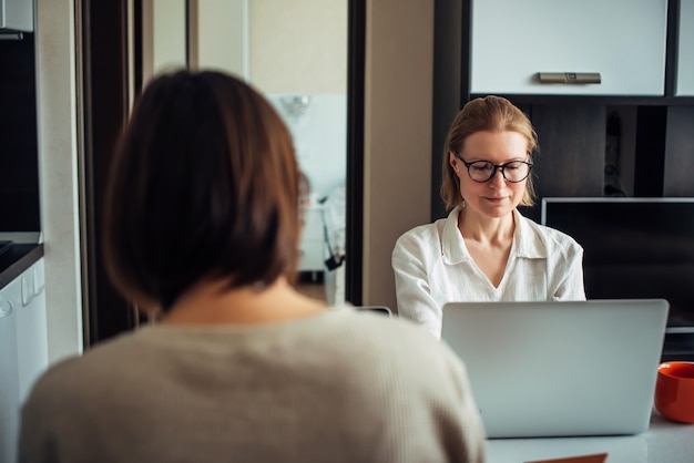 Twee volwassen meisjes die aan laptops in huisbinnenland werken. Freelance, coworking, werk, zelfstandige.