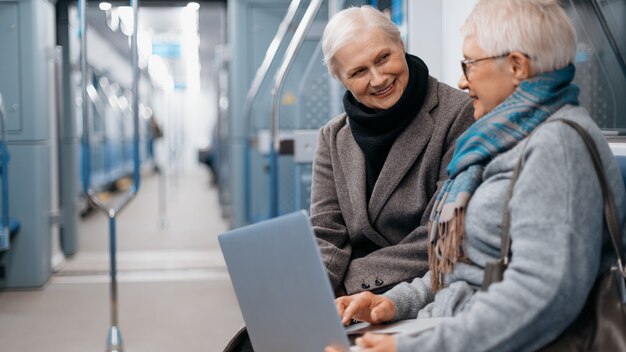 Twee volwassen vrouwen die een laptop gebruiken tijdens een metrorit