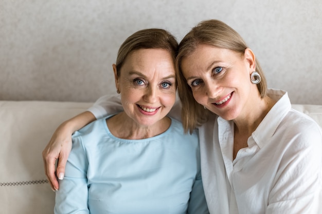 Foto twee volwassen vrouwen zitten elkaar op de bank te omhelzen