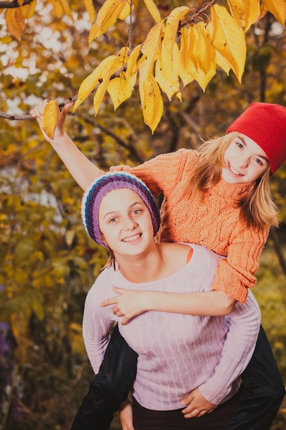 Twee vriendelijke zussen spelen met herfstbladeren en glimlachen