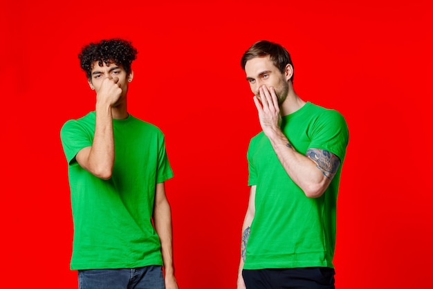 Twee vrienden bedekken hun hand gezicht emoties ongenoegen rode achtergrond