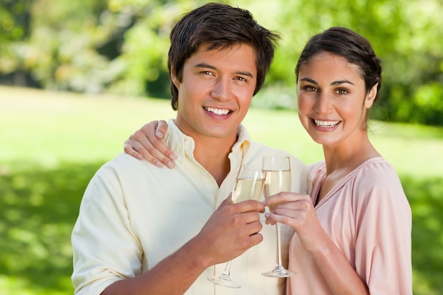 Twee vrienden die terwijl het raken van glazen champagne glimlachen