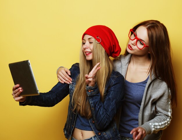 Twee vrienden die van hipstermeisjes selfie met digitale tablet nemen