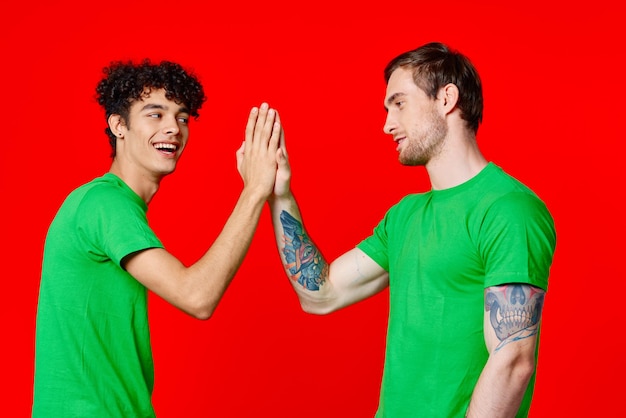 Twee vrienden in groene tshirts communicatie rode achtergrond studio