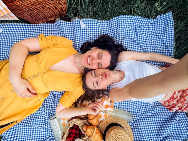 Twee vrienden maken een selfie op een blauwe deken voor een buitenpicknick