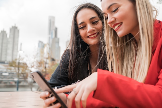 Twee vrienden met behulp van hun mobiele telefoon zittend in de coffeeshop.