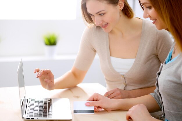 Twee vrienden of zussen praten aan tafel met laptop