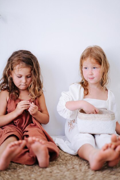 Foto twee vriendinnen die op de vloer zitten en iets uit een doos halen en samen tijd doorbrengen.