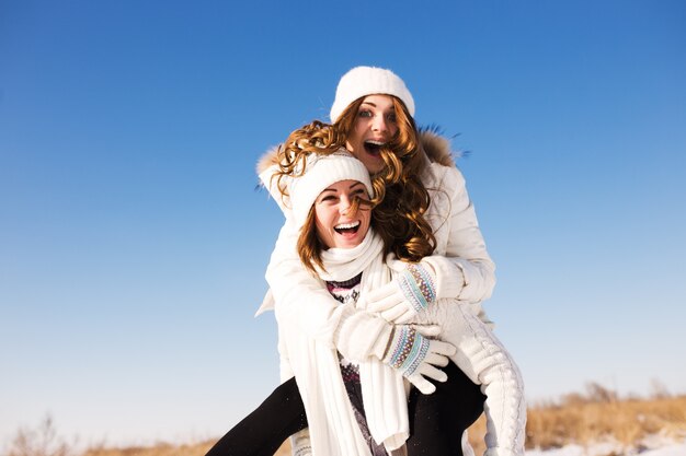 Twee vriendinnen hebben plezier en genieten van verse sneeuw op een mooie winterdag