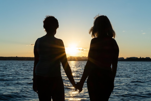 Twee vriendinnen lopen langs het strand hand in hand op een zomerdag genietend van de zomervakantie