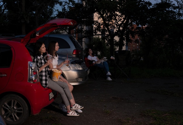 Twee vriendinnen met popcorn in de auto zitten tijdens het kijken naar een film tijdens het rijden in de bioscoop Selectieve focus Entertainment vrijetijdsbesteding hobby concept