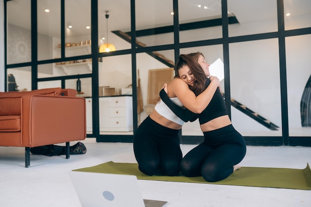 Twee vriendinnen omhelzen elkaar na yoga