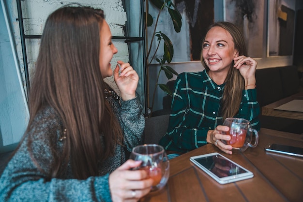 Twee vriendinnen praten in café terwijl ze een kopje thee drinken. ontmoetingsconcept