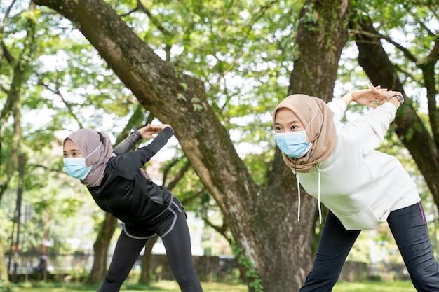 Twee vriendinnen van moslimvrouwen oefenen samen en dragen een masker voor bescherming tegen virussen
