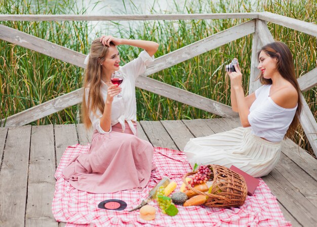 Twee vrolijke jonge vrouwen hebben een picknick buiten op een zomerse dag.