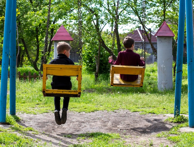 Twee vrolijke jongens rijden op schommel