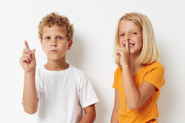 Twee vrolijke kinderen poseren handgebaar glimlach vrijetijdskleding lichte achtergrond