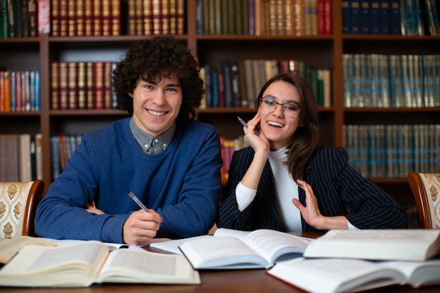 Twee vrolijke studenten voeren samen het project uit in de bibliotheek