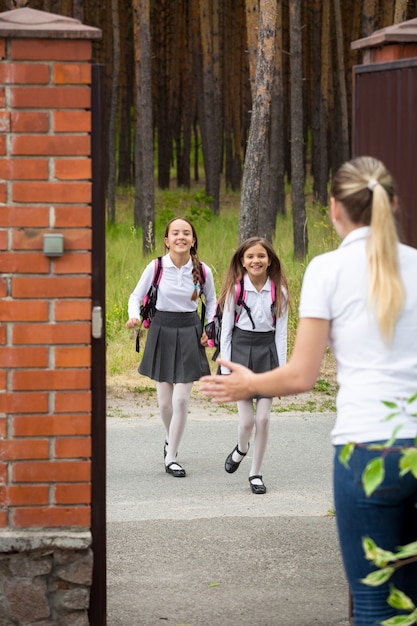 Twee vrolijke vrolijke meisjes die na school naar hun moeder rennen